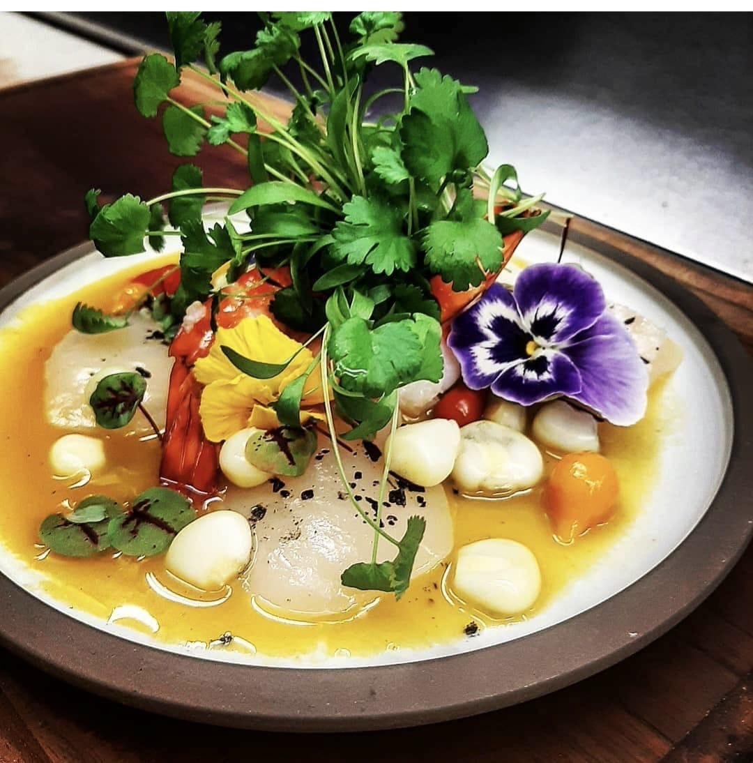 Scallop and prawn ceviche in citrus leche de tigre with corn, cilantro and edible flowers