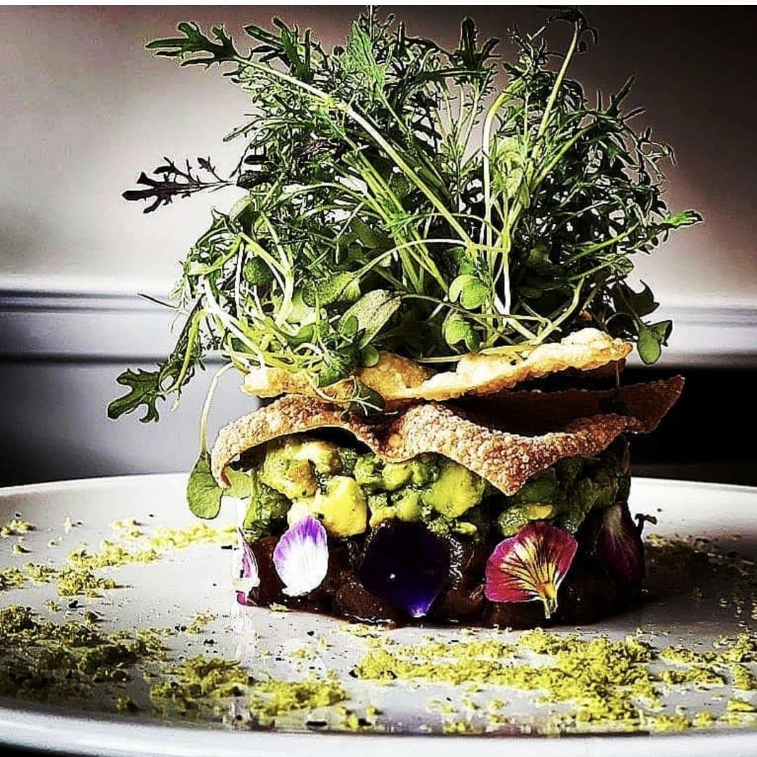 Layered tartare with avocado, crisp pastry shards, micro greens and edible flowers